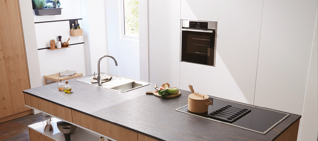 Kücheninsel aus Holz mit dunkler Arbeitsplatte, Spüle und Kochfeld