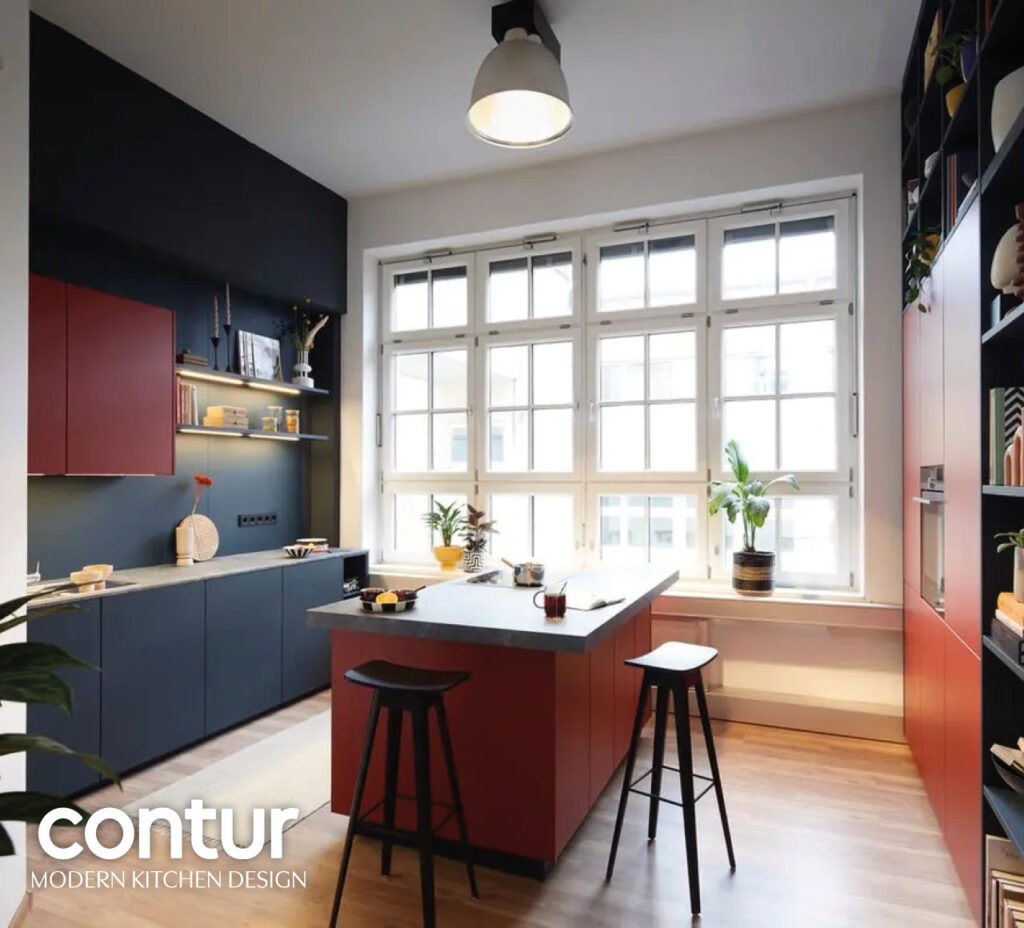 Moderne Küche mit farbigen Fronten, Insel und Sitzplätzen am Fenster