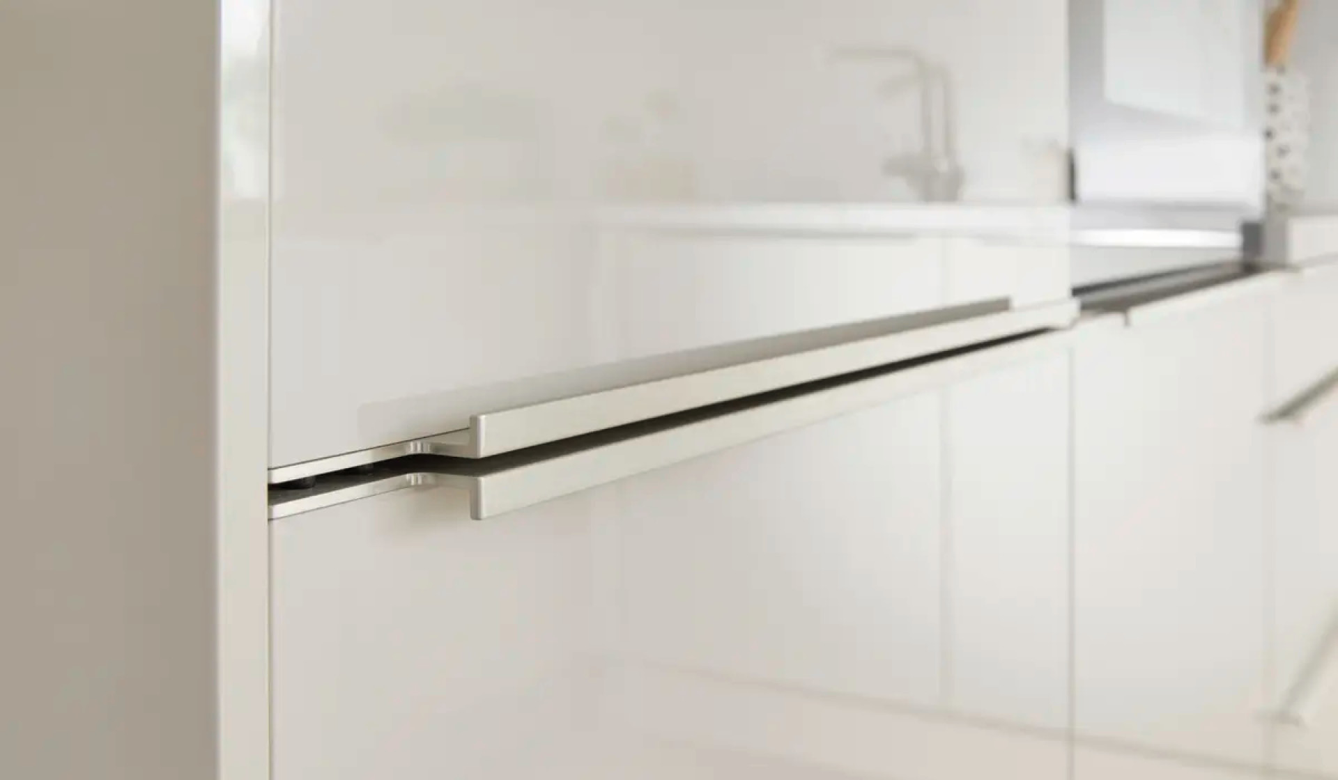 Detailaufnahme: Griffleiste an weisser Kuchefront,