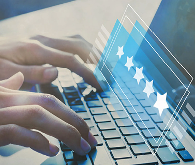Hände tippen auf Laptop Tastatur während eine digitale Sterne Bewertung angezeigt wird. Symbolbild für Online Bewertung, Kundenfeedback und Bewertungssystem im Internet.