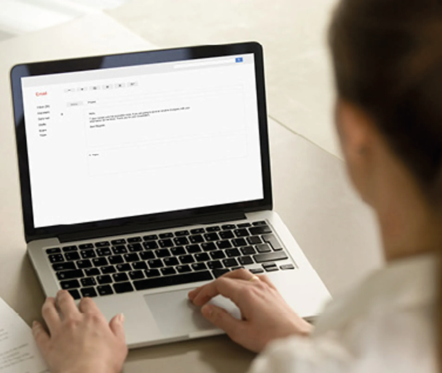 Person sitzt vor Laptop und schreibt eine E Mail oder Online Bewertung. Symbolbild für Kundenfeedback, Kontaktaufnahme und digitale Kommunikation mit Unternehmen.