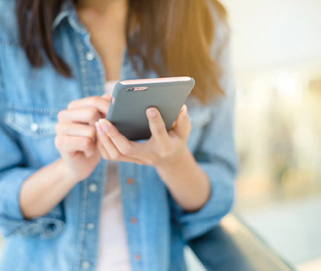 Frau nutzt Smartphone in der Hand und schreibt eine Nachricht oder Bewertung. Symbolbild für mobile Online Bewertung, Kundenfeedback und digitale Kommunikation.