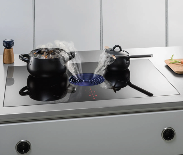 Zwei Töpfe auf einem modernen Induktionskochfeld. Wasserdampf steigt aus den Töpfen auf. Energieeffizientes Kochen mit moderner Küchentechnik.