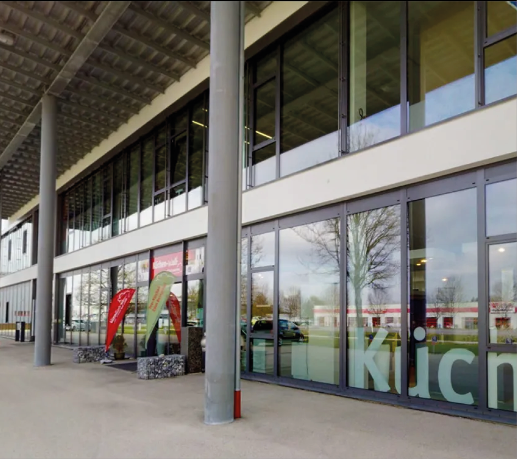 Außenansicht des Küchenstudios himmlisch wohnen in Kaufbeuren mit großer Glasfassade und Eingang zur Küchen Ausstellung für individuelle Küchenplanung und Beratung