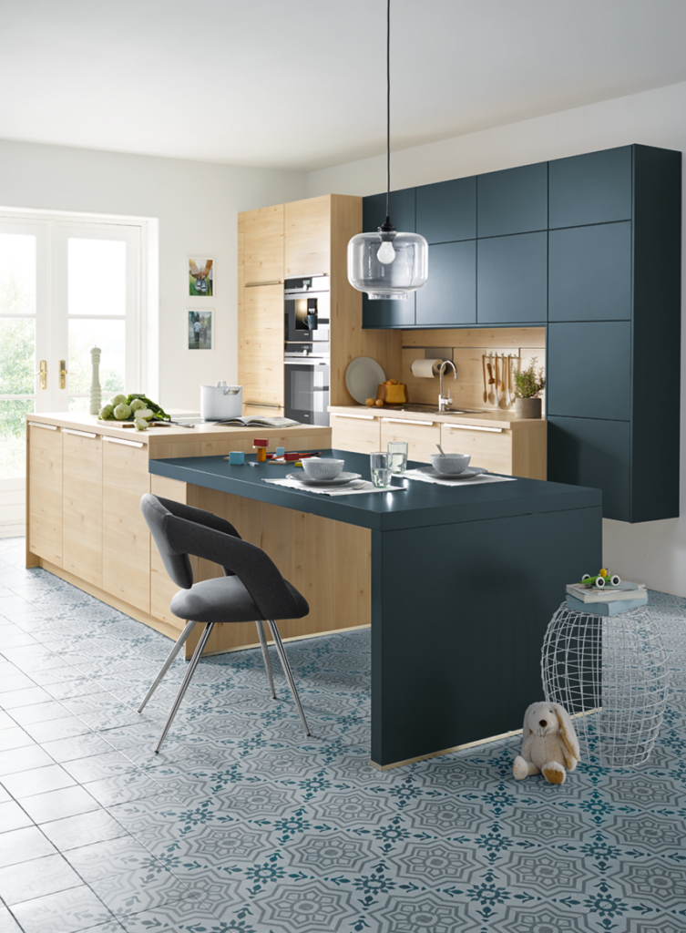 Moderne Ausstellungsküche mit Holzfronten, dunkler Arbeitsplatte und Kochinsel mit Sitzplatz als Beispiel für hochwertige Küchenplanung und modernes Küchendesign