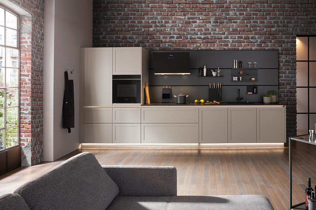 Loft Küche mit Backsteinwand, heller Küchenzeile und schwarzer Arbeitsplatte. Moderne Einbauküche mit integriertem Backofen und offenen Regalen.