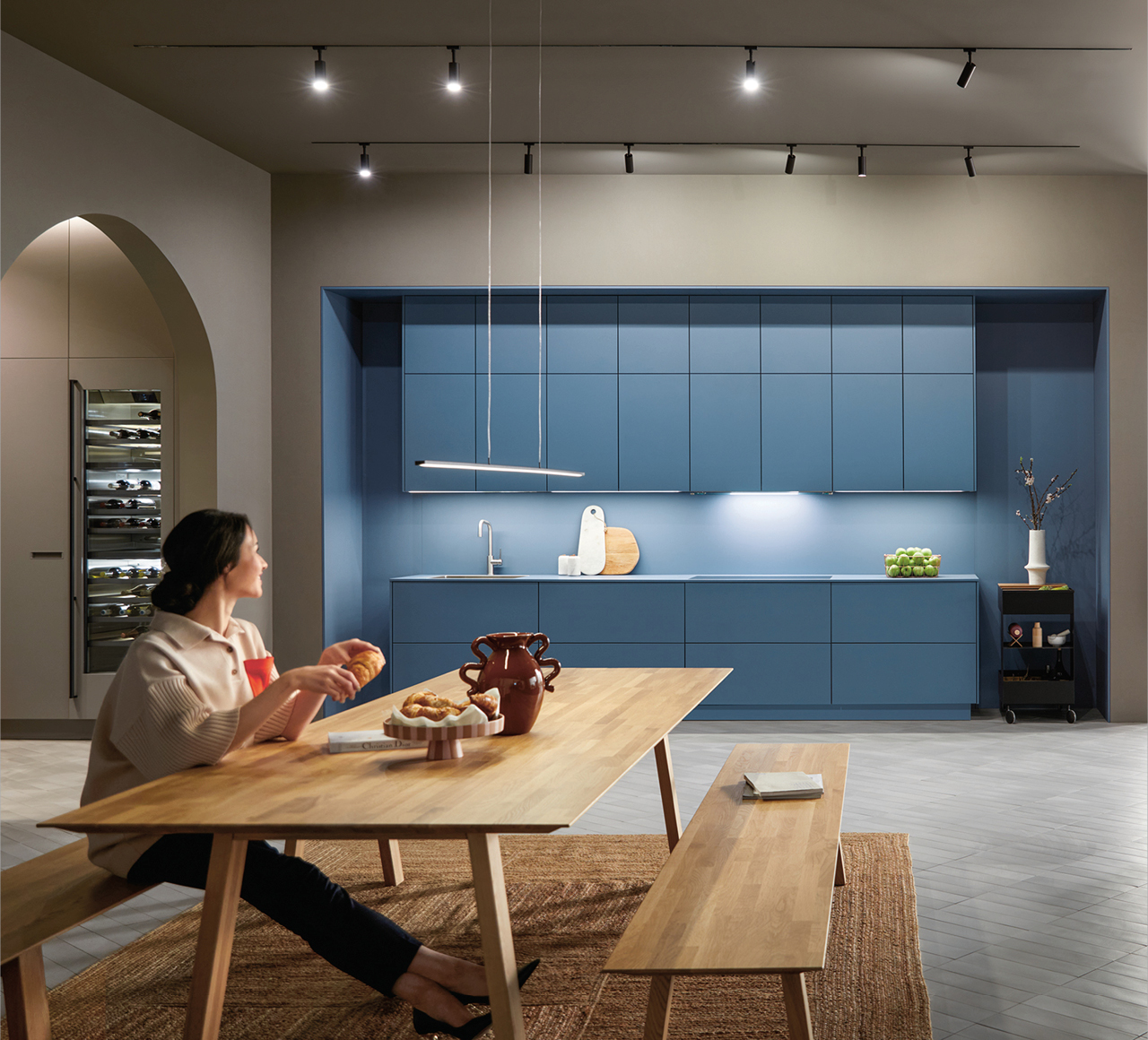 Große Designküche mit blauen Küchenfronten, Holz Esstisch und moderner Beleuchtung. Offene Wohnküche mit Küchenzeile und integriertem Weinkühlschrank.