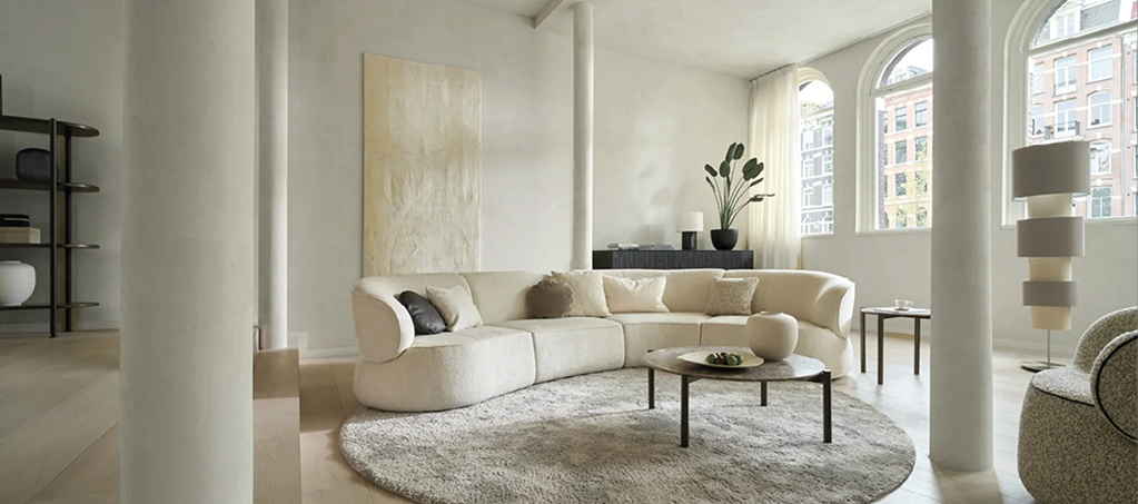 Stilvolles Wohnzimmer mit beigem Rundsofa, rundem Teppich und minimalistischem Couchtisch. Moderne Wohnideen für elegante Einrichtungskonzepte.