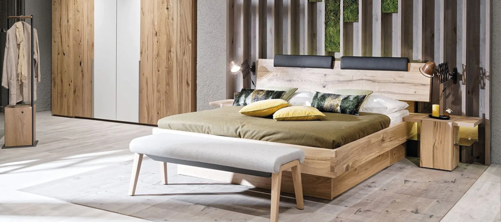 Schlafzimmer mit Massivholzbett, gepolsterter Sitzbank und Nachttischen aus Holz. Hochwertige Schlafzimmermöbel im natürlichen Design für modernes Wohnen.