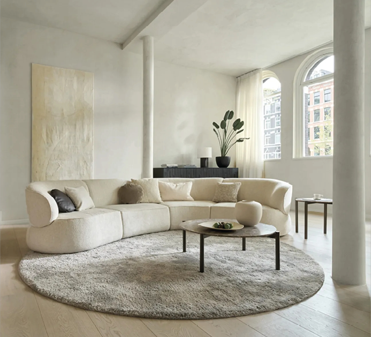 Stilvolles Wohnzimmer mit beigem Rundsofa, rundem Teppich und minimalistischem Couchtisch. Moderne Wohnideen für elegante Einrichtungskonzepte.