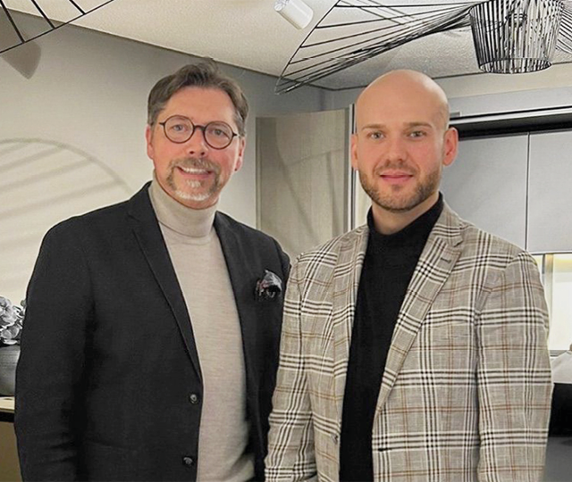 Zwei Küchenberater stehen in einer modernen Ausstellungsküche im Küchenstudio und beraten Kunden bei der individuellen Küchenplanung
