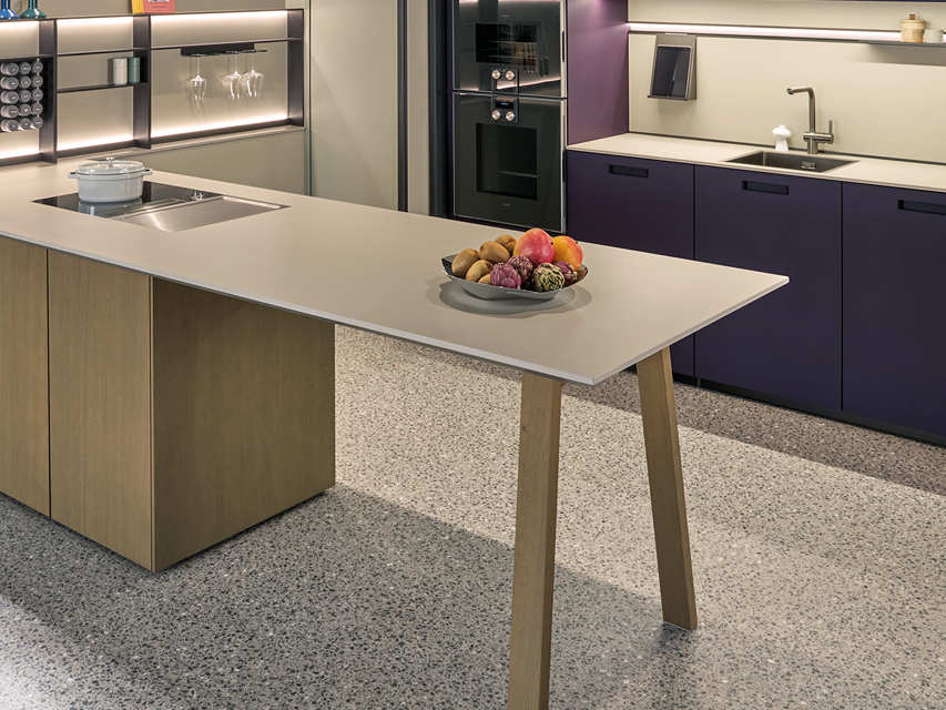 Offene Wohnküche mit Kücheninsel in Holzoptik und lila Fronten. Integrierte Geräte, Design Beleuchtung und hochwertige Materialien prägen die moderne next125 Küche.