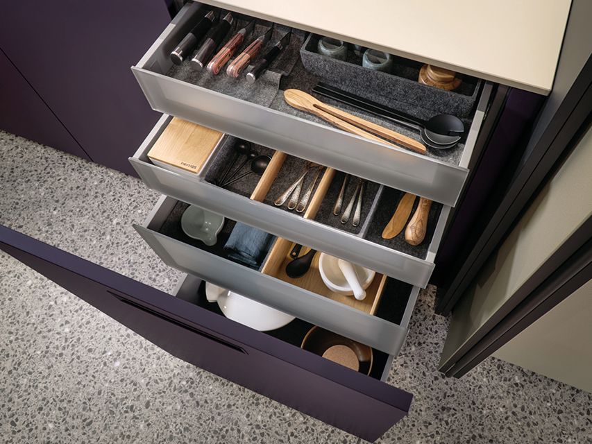 Geöffnete Küchenschublade mit Besteckeinsatz und Holzunterteilungen. Perfekte Ordnung durch intelligentes Organisationssystem in einer modernen next125 Design Küche.