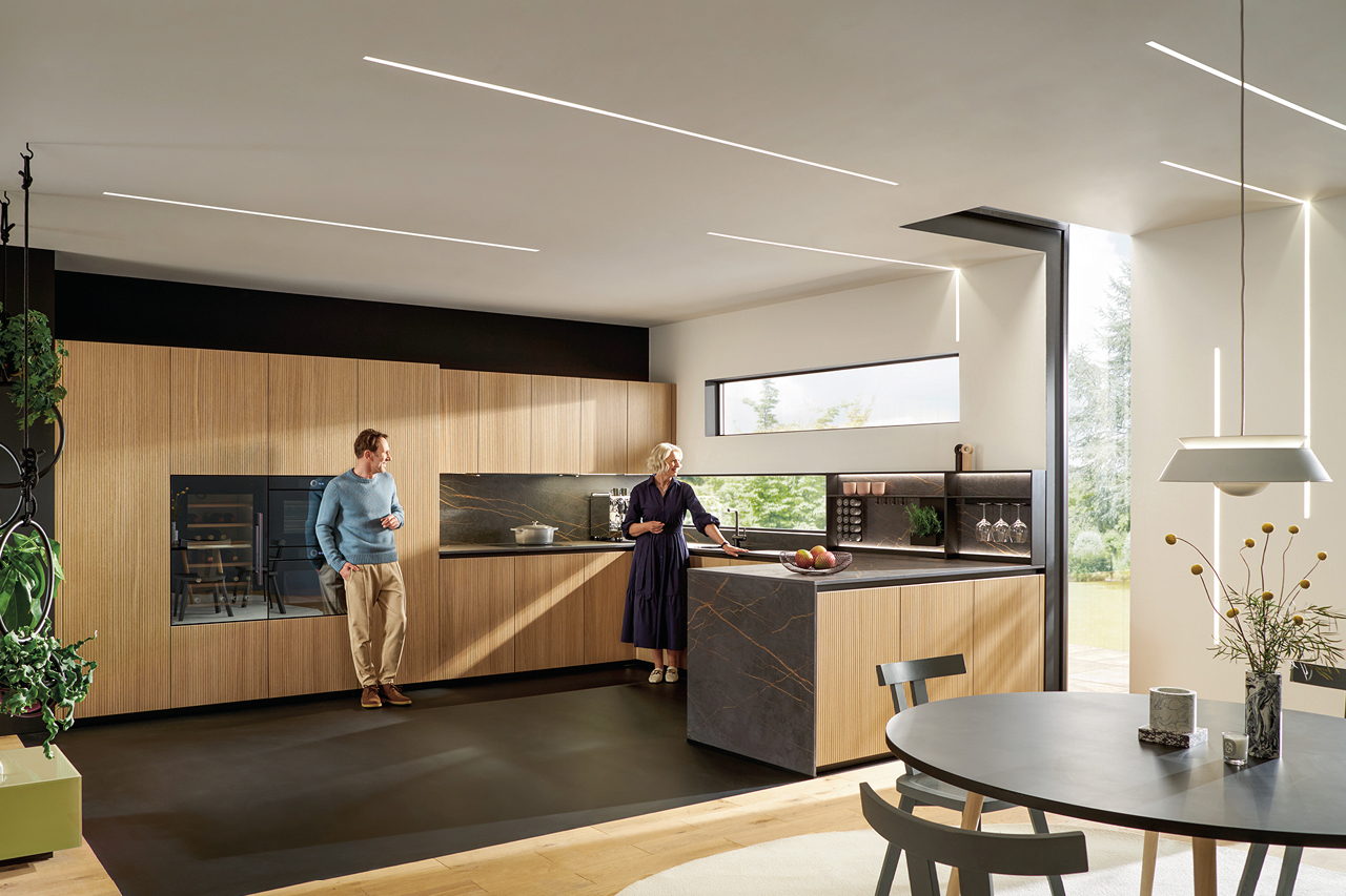 Großzügige offene Küche mit Kochinsel, Naturholz Fronten und dunkler Steinoberfläche. Modernes Küchendesign von next125 mit integriertem Backofen und viel Stauraum.