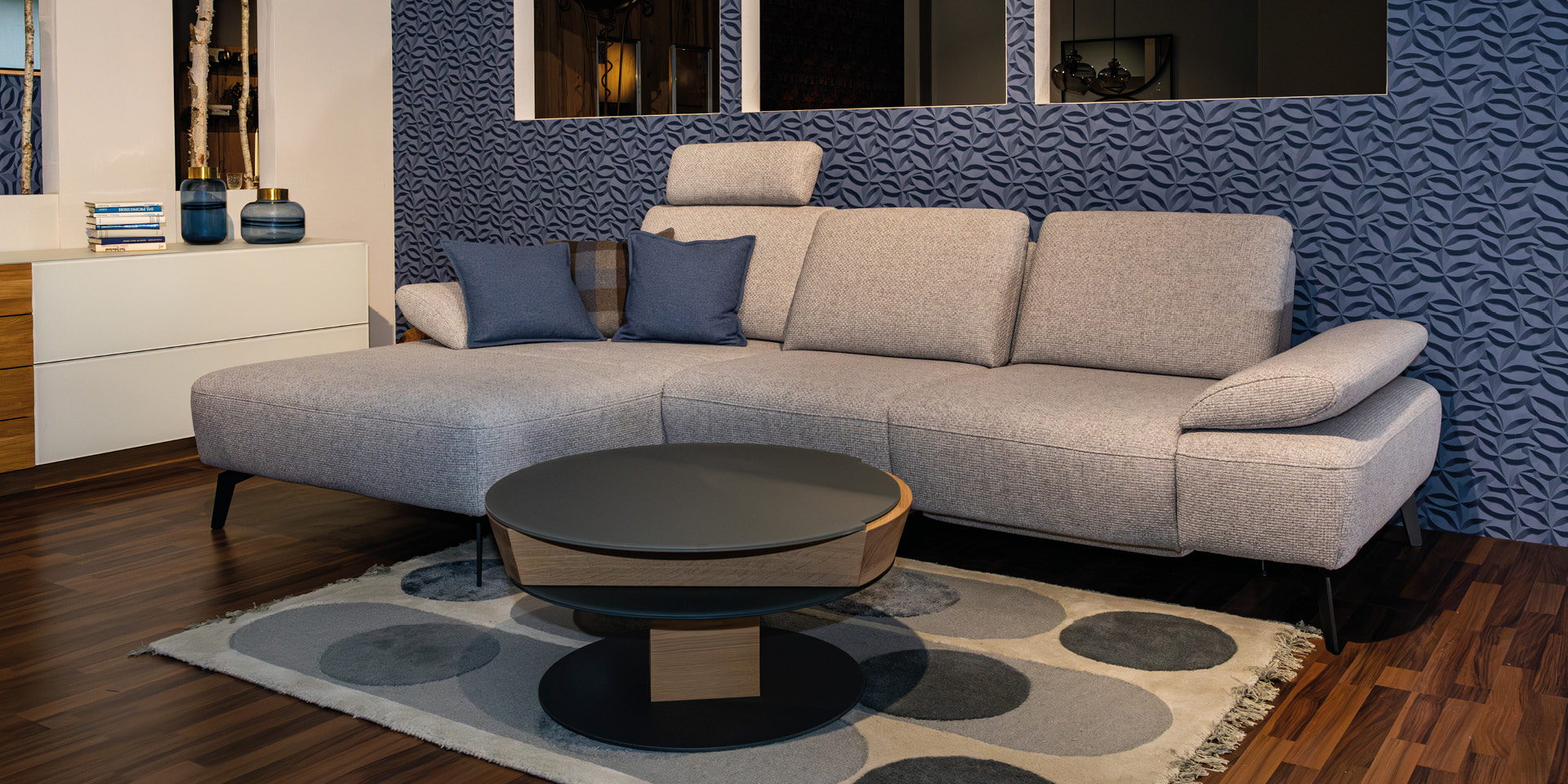 Graues Ecksofa mit Kissen und rundem Couchtisch im Wohnraum