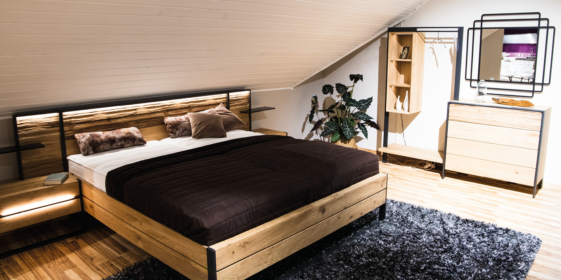 Schlafzimmer unterm Dach mit Holzbett, Kommode und Garderobenbereich
