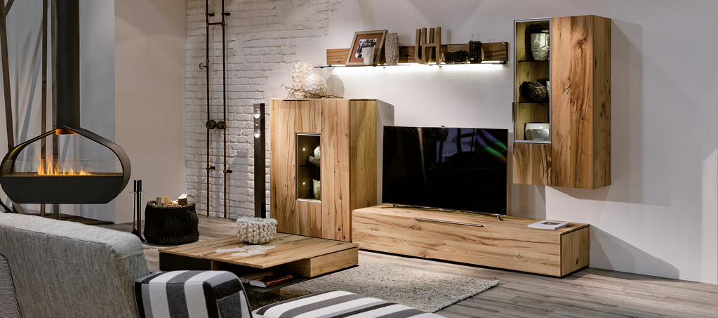 Wohnzimmer mit Massivholz-Wohnwand, TV-Board und Hängeschrank, modern beleuchtet.