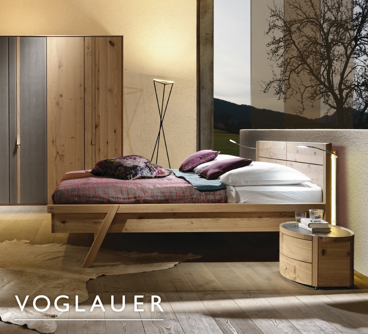 Schlafzimmer mit Massivholzbett, Schrank und „Voglauer“-Schriftzug im Header.