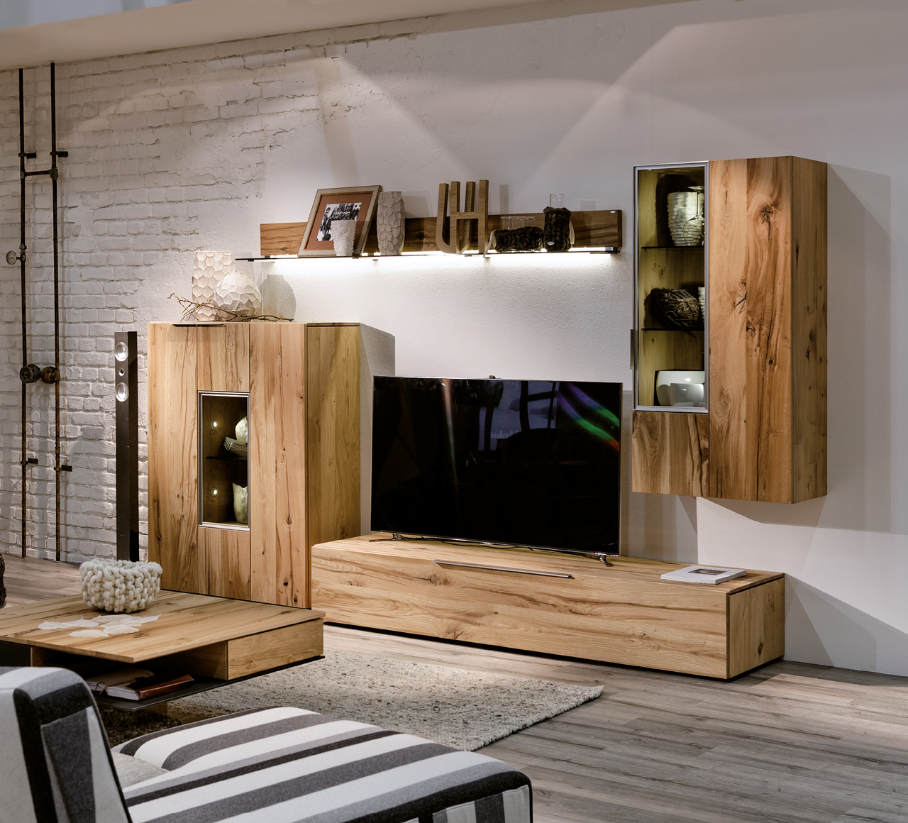 Wohnzimmer mit Massivholz-Wohnwand, TV-Board und Hängeschrank, modern beleuchtet.