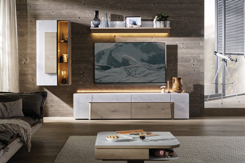 Wohnzimmer mit TV-Board, Hängeregal und Vitrine vor Holzvertäfelung.
