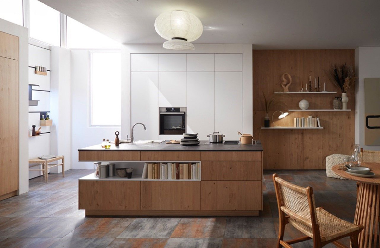 Küche mit großer Holzinsel mittig, weißen Schränken hinten und offenen Regalen rechts, Esstisch vorne rechts