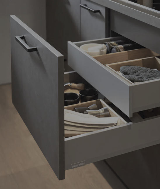 Geöffnete Schubladen mit Einsätzen für Geschirr und Küchenutensilien, Front in Grau mit Griff