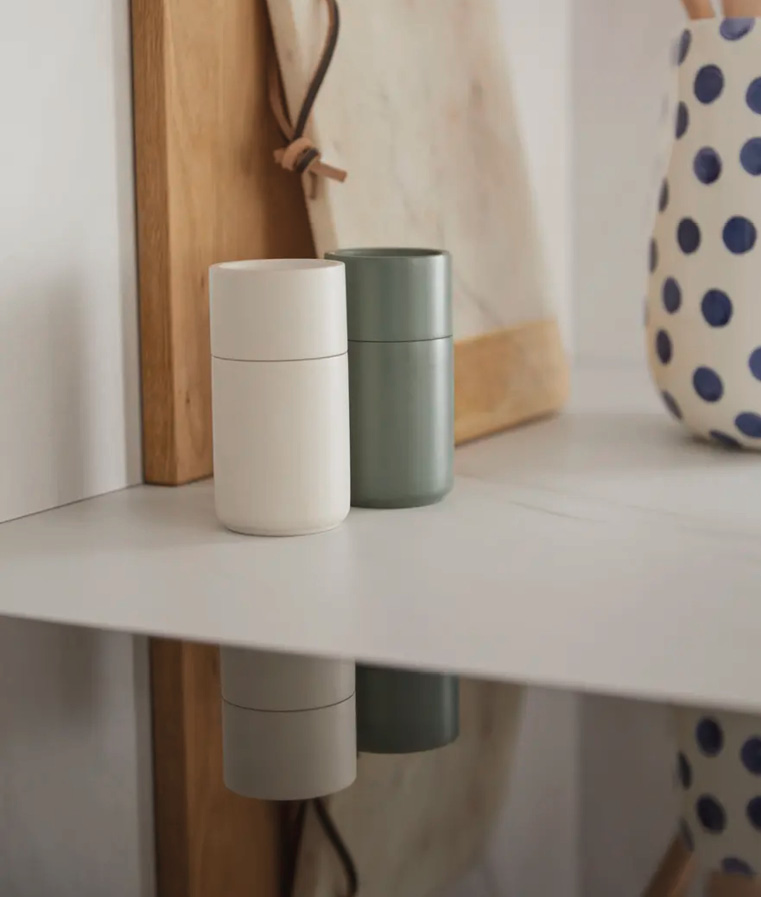 Zwei Vorratsdosen auf Arbeitsplatte, dahinter Schneidebrett und Keramikbehälter mit Punkten