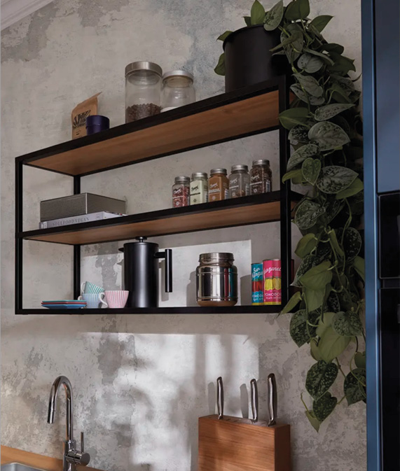 Wandregal mit Gewürzgläsern, Tassen und Pflanze rechts, darunter Spüle und Messerblock auf Arbeitsplatte