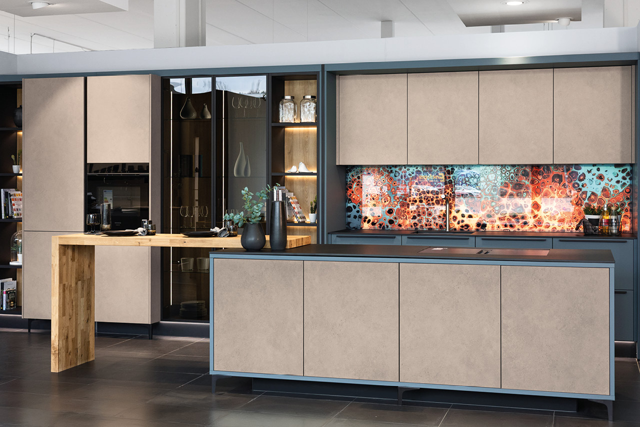 Moderne next125 Küche mit Kücheninsel und farbiger Glasrückwand.