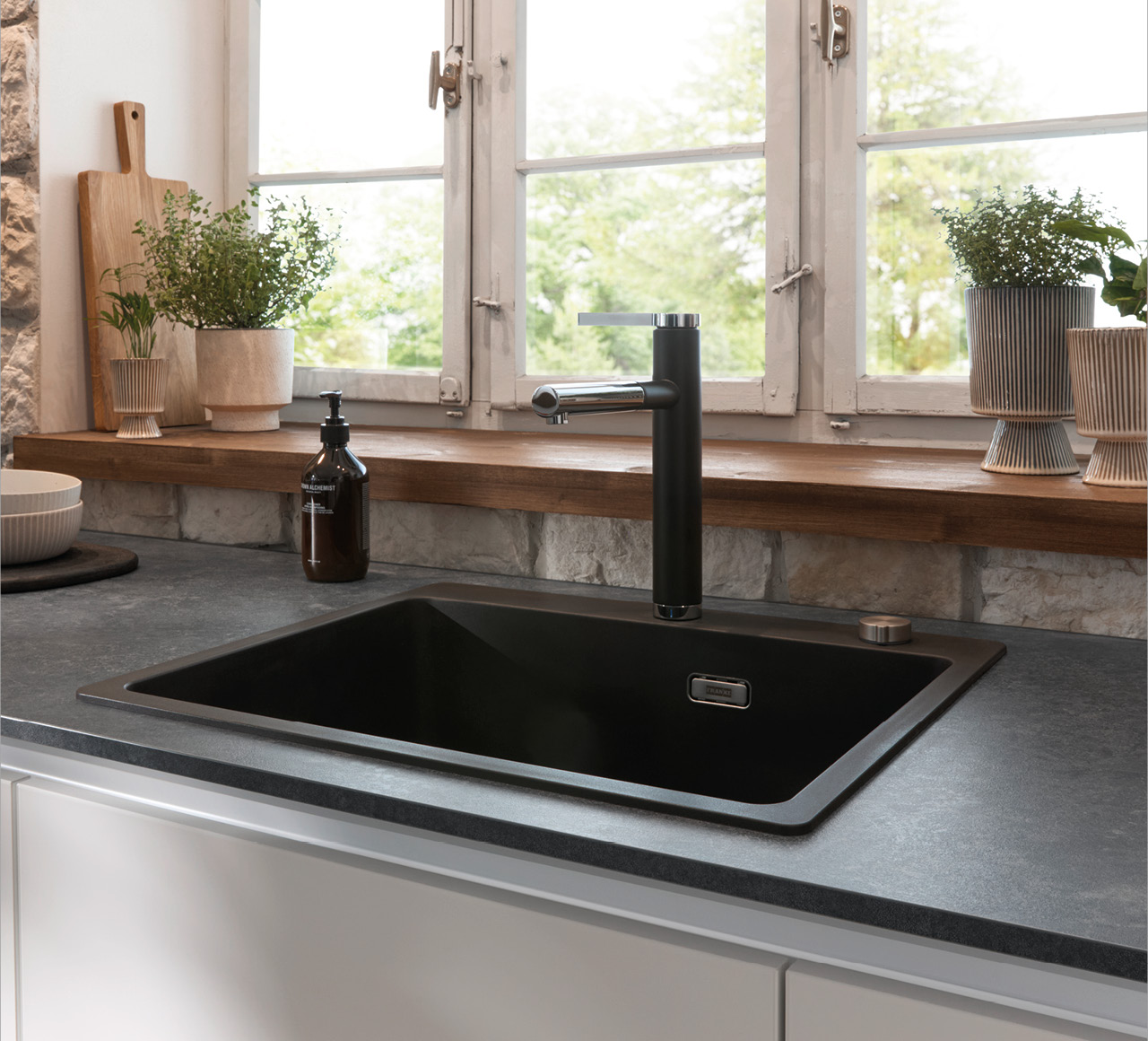 Moderne Küchenspüle mit schwarzem Becken und Armatur am Fenster
