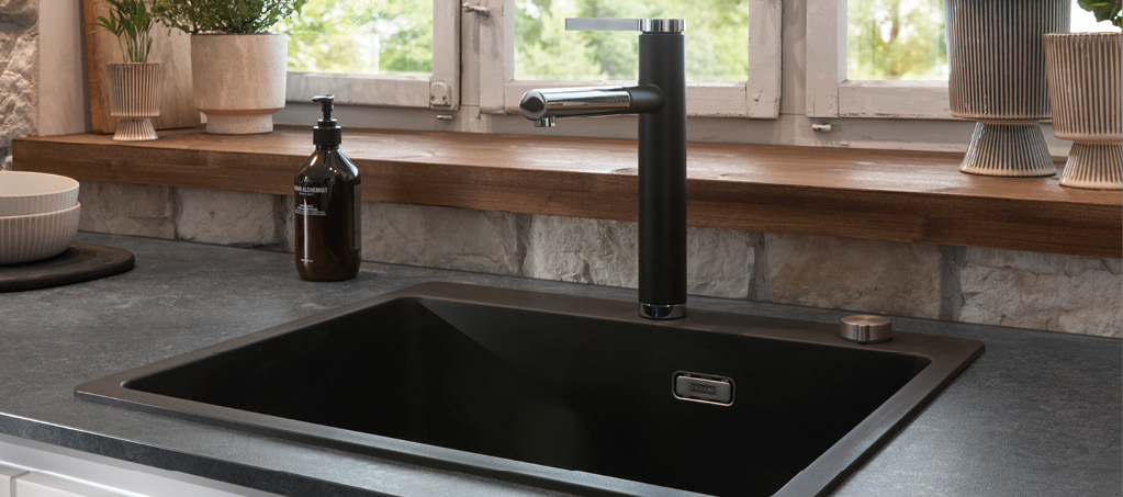 Moderne Küchenspüle mit schwarzem Becken und Armatur am Fenster