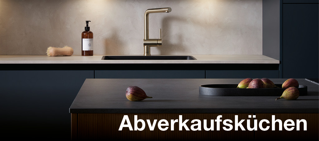 Dunkle Designküche mit Spüle und Schriftzug „Abverkaufsküchen“