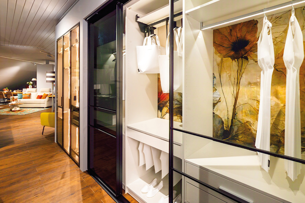 Offener Kleiderschrank mit Beleuchtung Offener Kleiderschrank mit Beleuchtung, weißen Regalen, Kleidung und großem Blumenbild