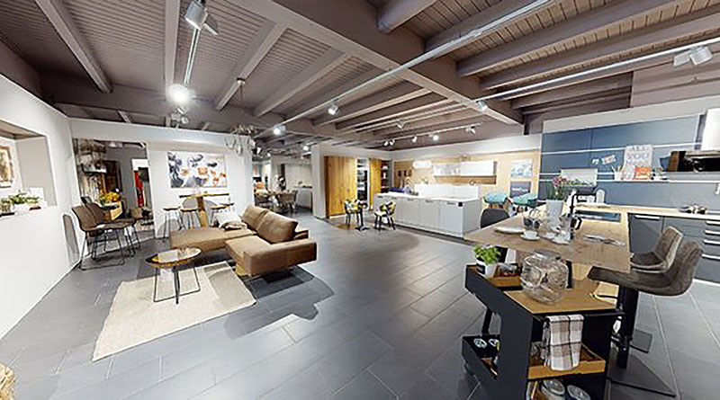 Showroom mit Einbauküche, Sofa, Esstisch, Stühlen und grauem Fliesenboden